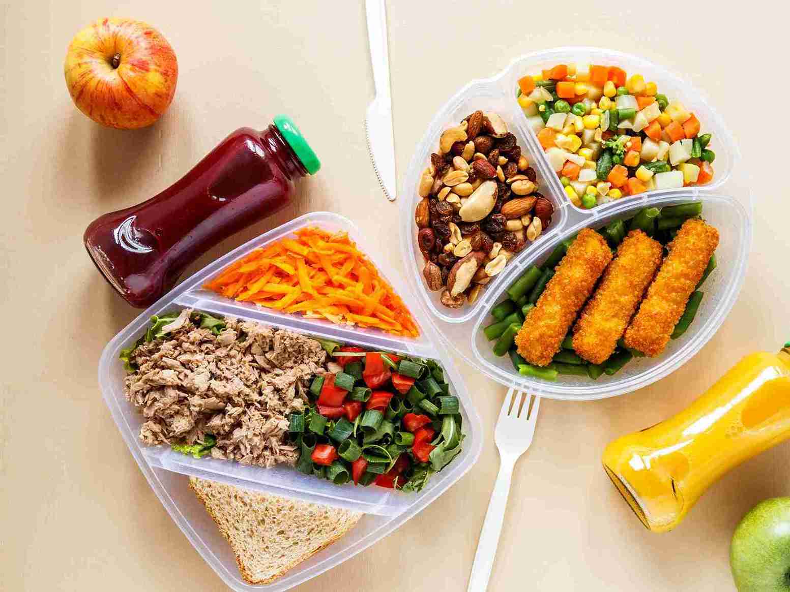 wanita memegang kotak bekal berisi nasi, sayur, lauk sehat, dan buah