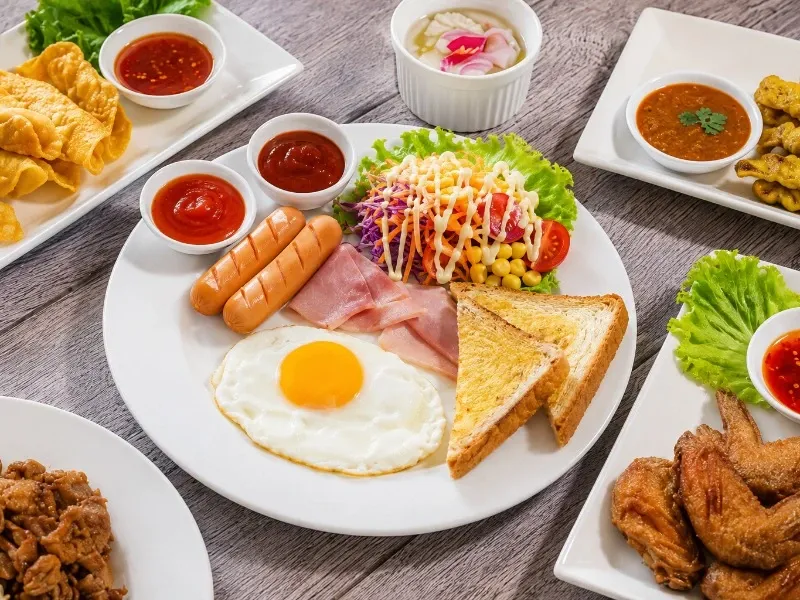 Ilustrasi menu sarapan pemicu risiko penyakit jantung seperti mi instan, sosis, donat, dan gorengan.